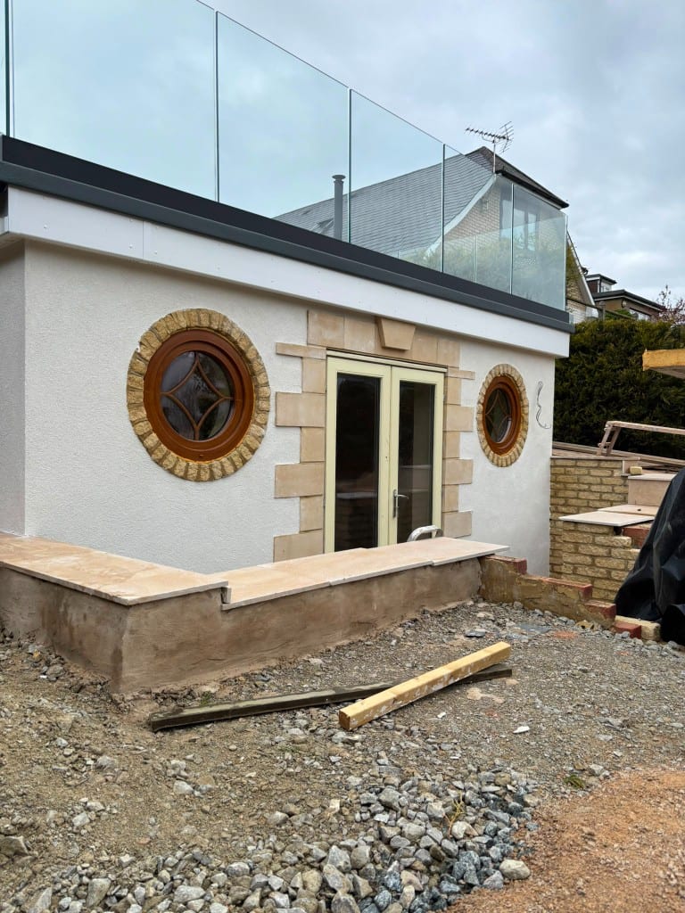 Premium render extension with stone detailing and round windows in Kent